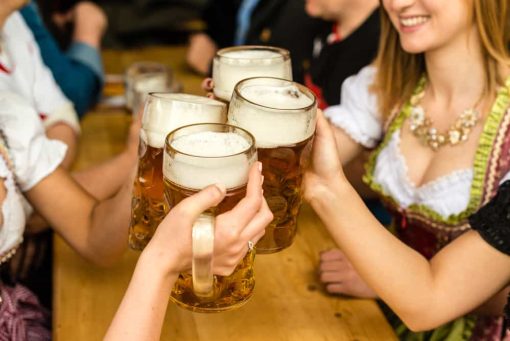 women in bavarian attire with mugs of beer